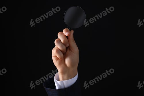 Preview: Magnifying glass in male hand in suit on black background