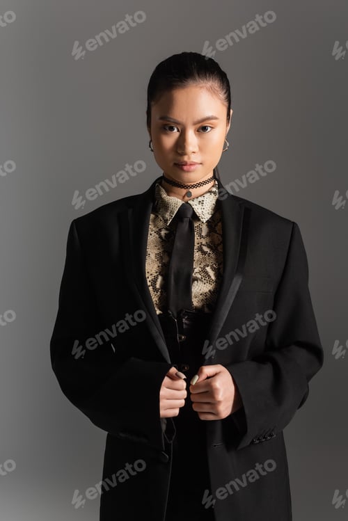 Preview: Stylish asian model in jacket looking at camera isolated on grey