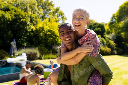 Preview: Portrait of happy diverse couple giving each other piggyback rides and smiling in garden
