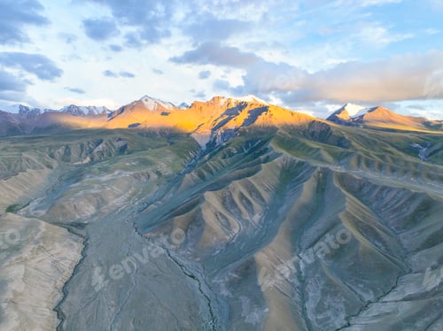 Preview: Golden hour on mountain slopes above a wide dry riverbed