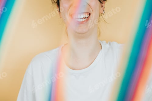 Preview: Young woman smiling happily to camera while holding a LGBTIQ flag waving to camera