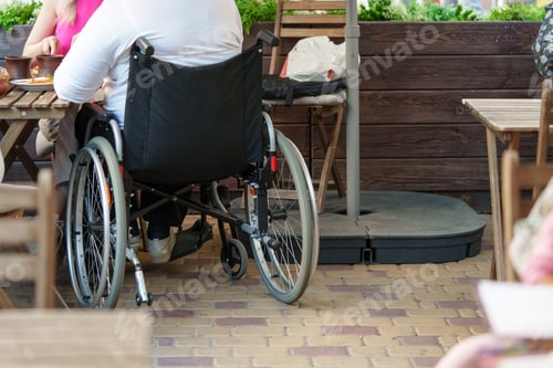 Preview: Unrecognizable woman with disability sitting in wheelchair in the street close up