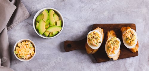 Preview: Canapes with deviled eggs on toast on a board on the table top view web banner