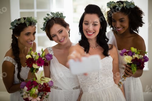 Preview: Bride and bridesmaid taking selfie at home