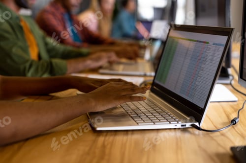Preview: Mid section of diverse male and female creative colleagues working using computers in office