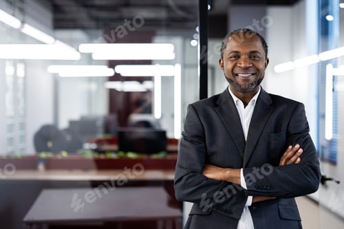 Preview: Confident businessman standing with arms crossed in modern office space, showcasing leadership and