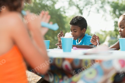 Preview: Children sitting at picnic table at birthday party