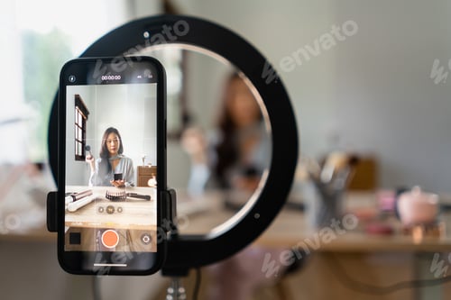 Preview: Beauty blogger reviewing powder product while recording video on smartphone for makeup vlogger