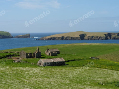 Preview: View of a traditional stone farmhouse located in a hilly, green valley on the coast