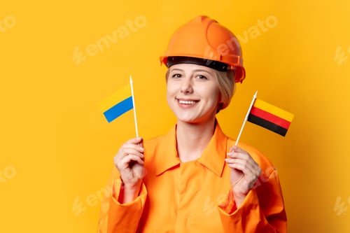 Preview: worker in helmet and orange overalls with two Ukrainian and German flags