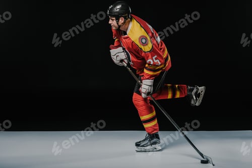 Preview: side view of young sportsman playing ice hockey on black