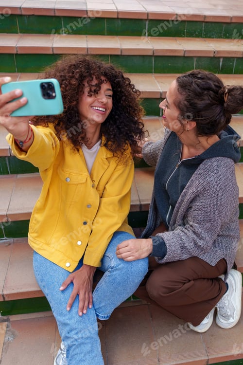 Preview: Happy young women capturing moments together, smiling for a selfie using a mobile phone