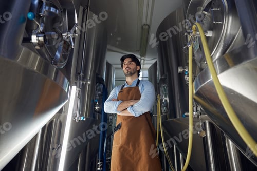 Preview: A man wearing an apron is standing with arms crossed in a factory