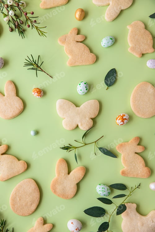 Preview: Easter cookies, candies shaped eggs, eucalyptus, flowers and quail eggs on green pastel background.