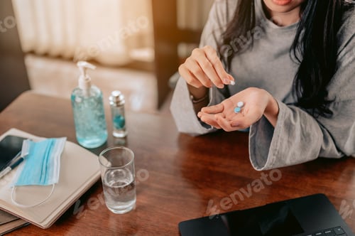 Preview: Pill in her hand. young woman holding a glass with water and pills in her hands.coronavirus.