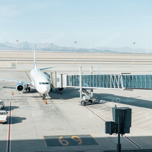 Preview: Beautiful plane with a landing bridge at the airport on a background of mountains, desert