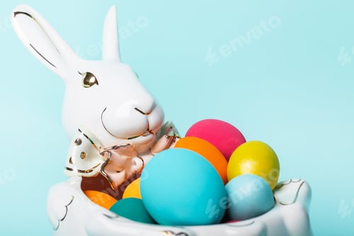 Preview: Colorful Easter eggs lie in a vase in the shape of a porcelain rabbit. Easter holiday concept