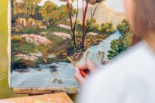 Preview: Hand painting with a brush on a canvas with a painting of a forest.