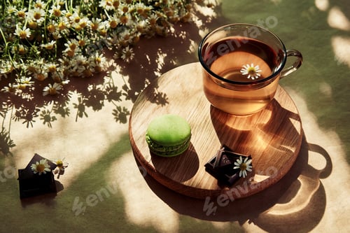 Preview: Aesthetic summertime brunch - chamomile natural tea,macaroon, chocolate under hard shadows.