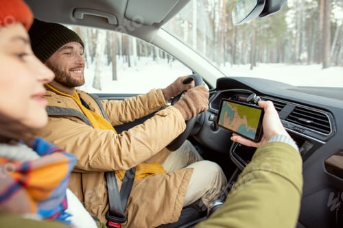 Preview: Happy young active man in warm winterwear looking at map on screen of smartphone