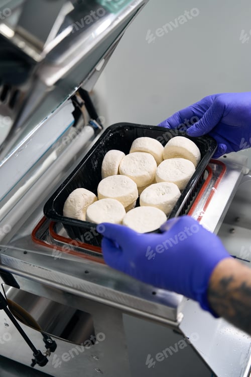 Preview: Worker in a semi-finished products workshop packs cottage cheese pancakes
