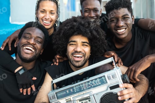 Preview: Happy group of multiracial people having fun listening music with vintage boombox outdoor