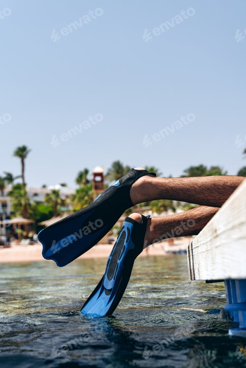 Preview: Legs resting in flippers, touching water. Active rest by the sea