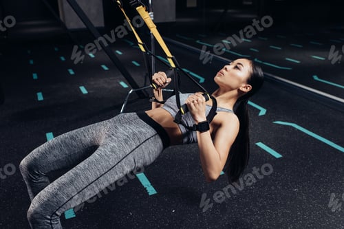 Vista previa: delgada deportista asiática entrenando con bandas de resistencia en un centro deportivo