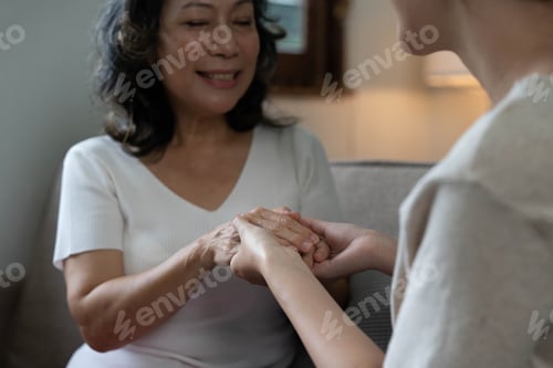 Preview: Happy adult granddaughter and senior grandmother having fun enjoying talk sit on sofa in modern
