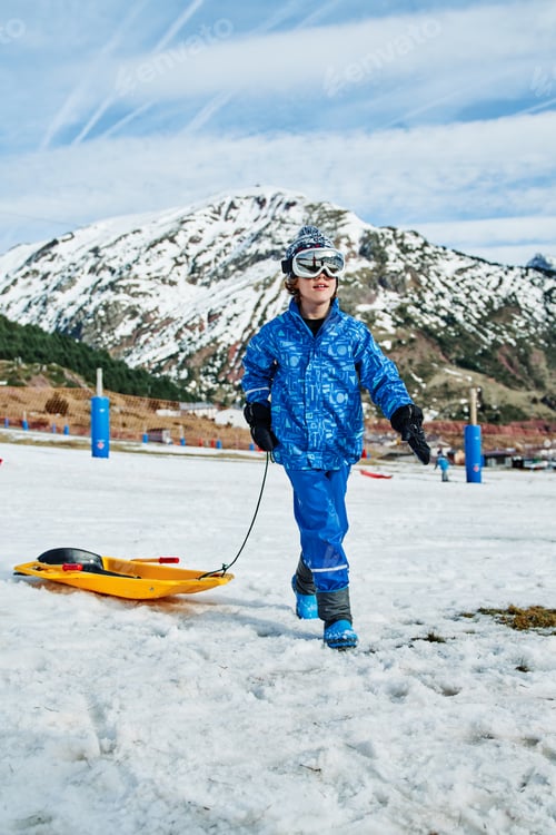 Preview: Boy with sledge in snowy mountains