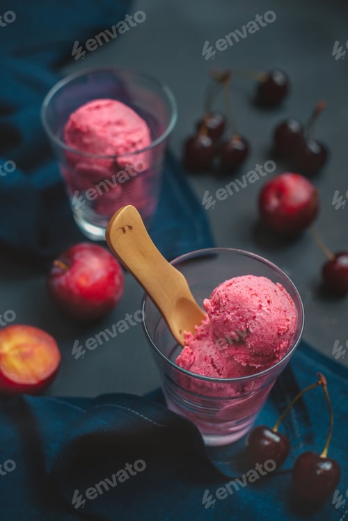 Preview: Homemade pink ice cream in transparent glasses with cherries and plums. Dark food photography with