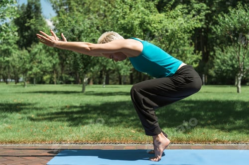 Preview: side view of woman practicing yoga on yoga mat in park