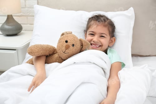 Preview: Cute child with stuffed bunny resting in bed at hospital