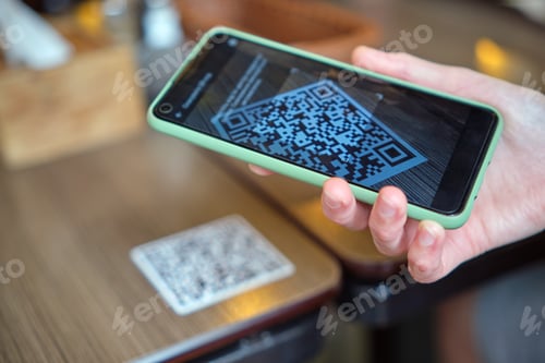 Preview: Closeup of guest hand ordering meal in restaurant while scanning qr code with mobile phone for