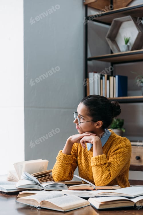 Preview: thoughtful young student girl preparing for exam at library and looking at window