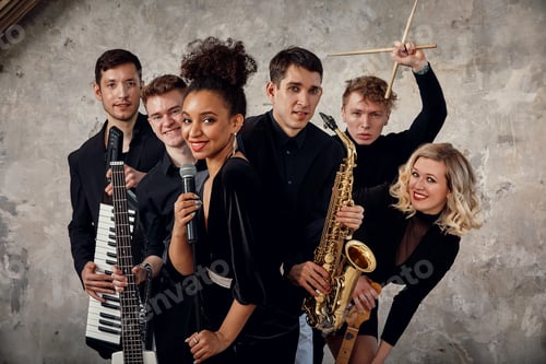 Preview: Portrait of diverse group of young people musical band playing with instruments - on gray concrete