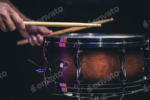 Preview: Drummer playing drum sticks on a snare drum on black background.