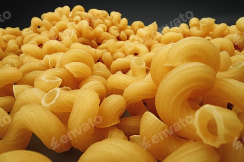 Preview: Uncooked pasta swirls on dark background macro