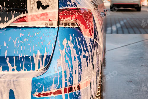 Preview: Close up a headlight in a soap during car washing with a foam. Cleaning a car using high pressure