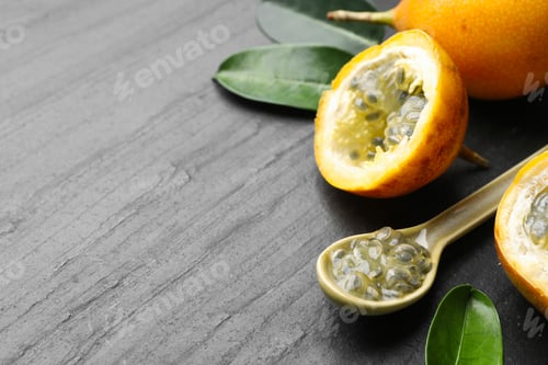Preview: Ripe passion fruits, seeds and green leaves on black table, closeup. Space for text