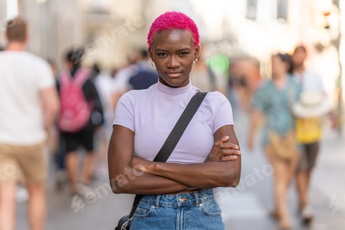 Preview: Serious afro woman looking at camera with the arms crossed outdoors
