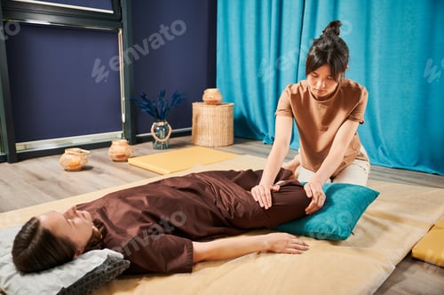 Preview: Masseuse making thai yoga massage treatment, stretching female patient's body.