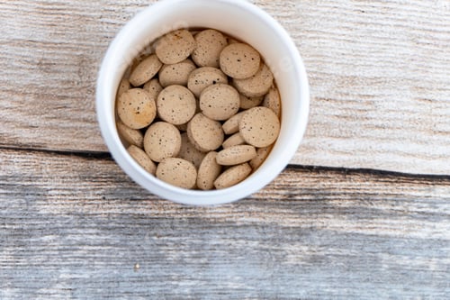 Preview: Top view close-up of a white bowl filled with brewer's yeast on a wooden background