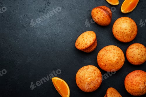 Preview: Appetizing orange muffins or cupcakes on black table background, winter homemade pastries, top view