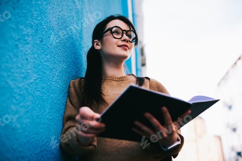 Preview: Glad woman with opened book on street