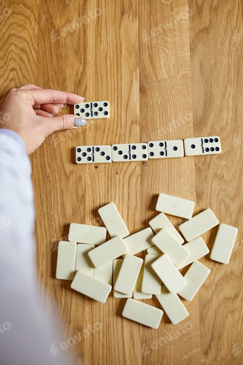 Preview: Top view of woman hand play white domino games on wooden table