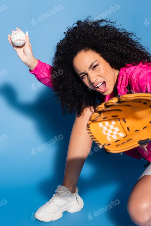 Preview: excited african american woman in leather glove holding baseball on blue