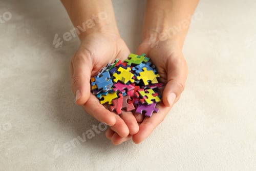 Preview: Сolored puzzles in hands on beige background