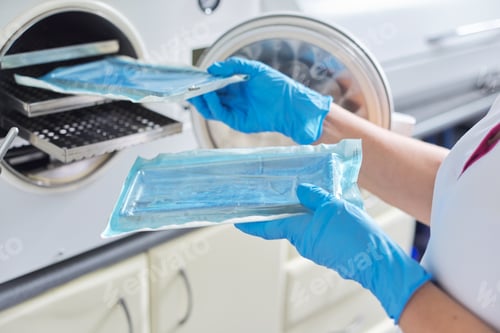 Preview: Female nurse doing sterilization of dental medical instruments in autoclave