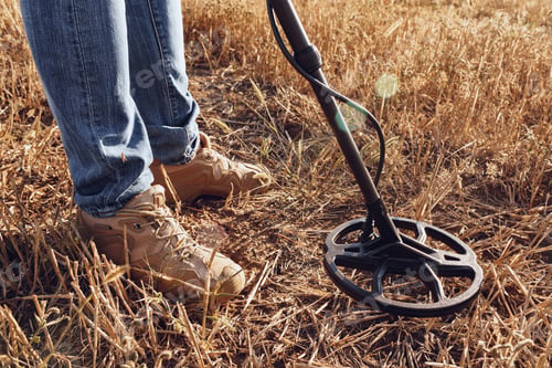 Preview: Man with metal detector equipment searching for metal goods in the field